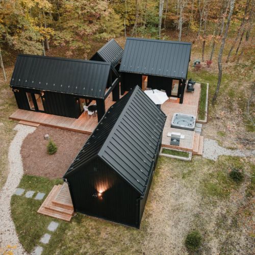 Ariel view of our deconstructed villa, Villa Pine featuring four structures - Eat & Play, Heat (Sauna) and two Rest & Refresh, connected by over 900 sqft of decking, including hot tub, fire pit, and EV charging.
