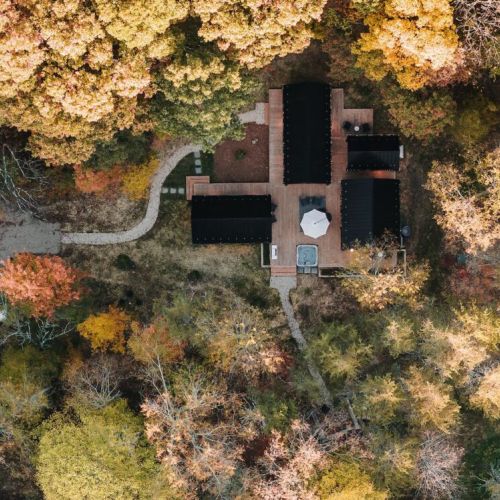 Ariel view of our deconstructed villa, Villa Pine featuring four structures - Eat & Play, Heat (Sauna) and two Rest & Refresh, connected by over 900 sqft of decking, including hot tub, fire pit, and EV charging.